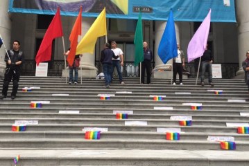 People hold candles and flags in Vancouver to remember the dead in Orlando