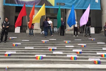People hold candles and flags in Vancouver to remember the dead in Orlando